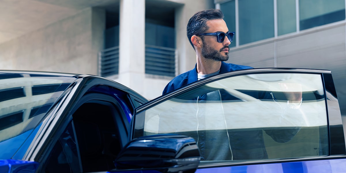A Man in Sunglasses Standing Next to a Parked Blue 2026 OPTIQ-V