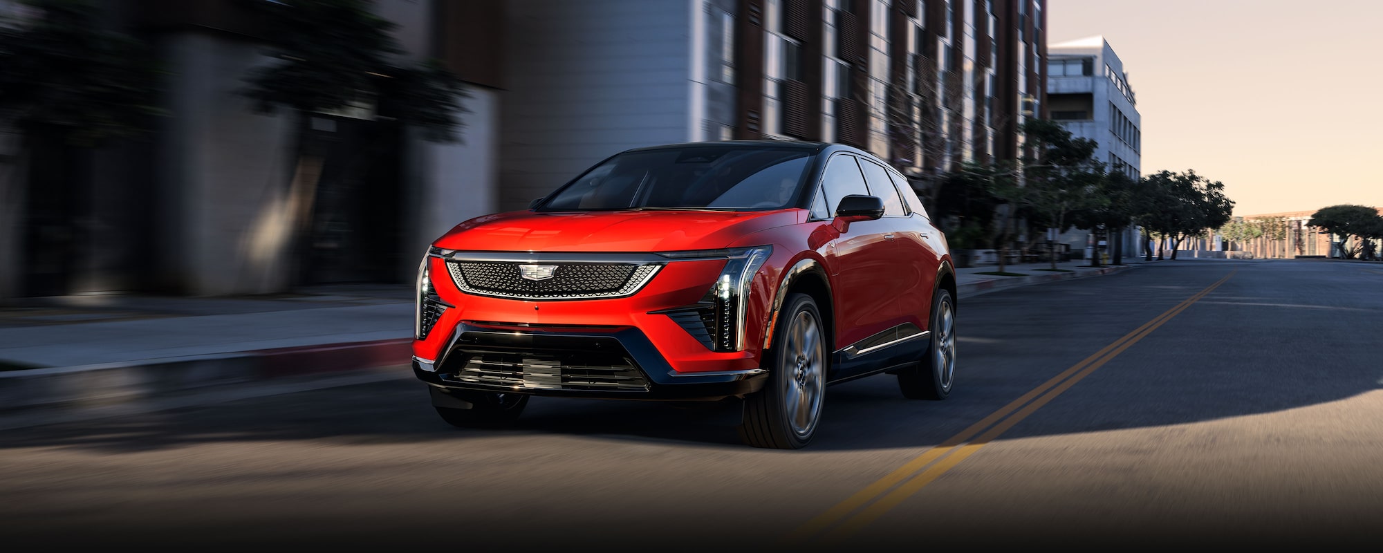 A Red 2026 Cadillac OPTIQ Driving Down a City Street