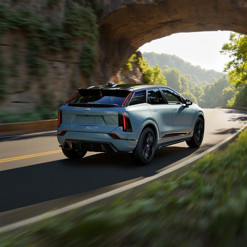 Rear View of a Blue 2026 OPTIQ-V Driving on a Curve of a Mountain Row