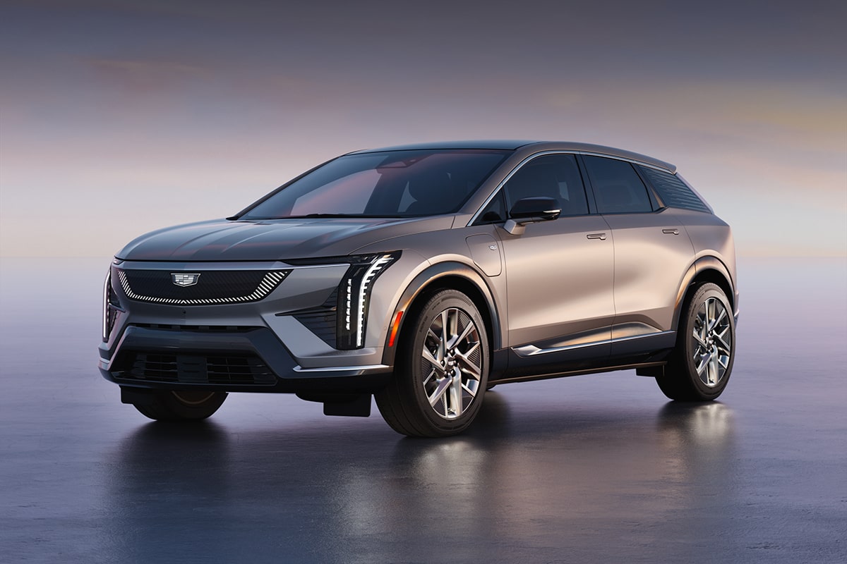 Three-quarters View of a Silver Cadillac OPTIQ Electric SUV Parked on a Smooth, Reflective Surface at Dusk