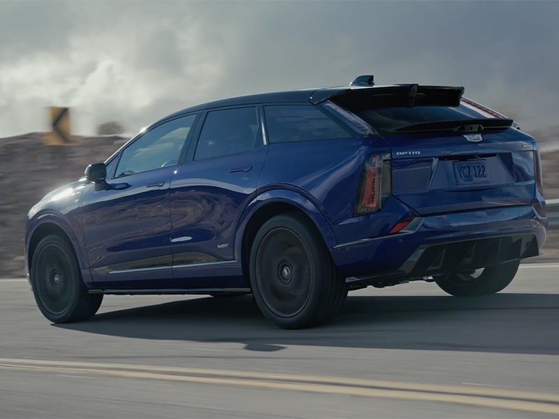 Rear Three-quarter View of the Cadillac OPTIQ-V Driving Down a Road