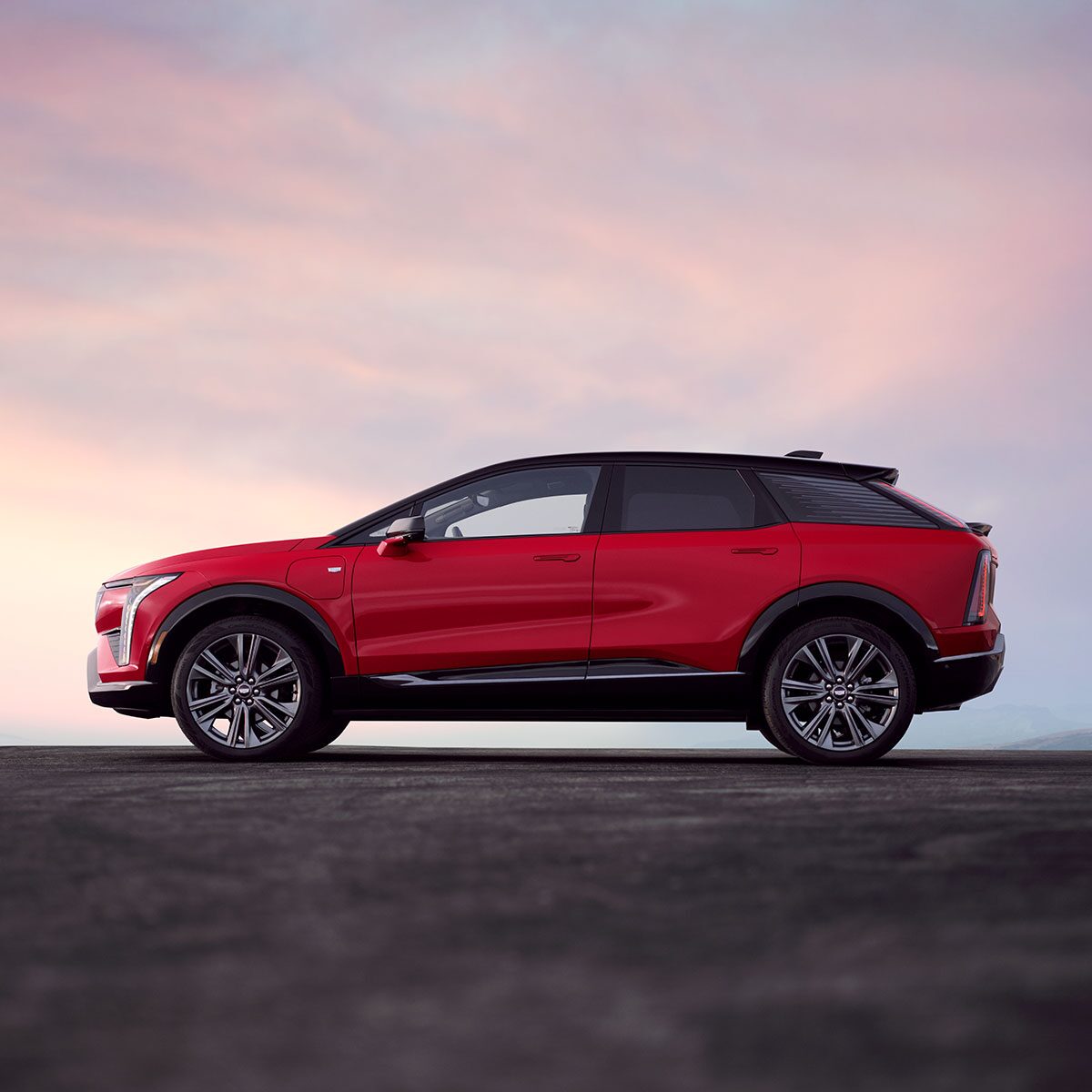 Profile View of a Red 2027 Cadillac OPTIQ During a Beautiful Sky