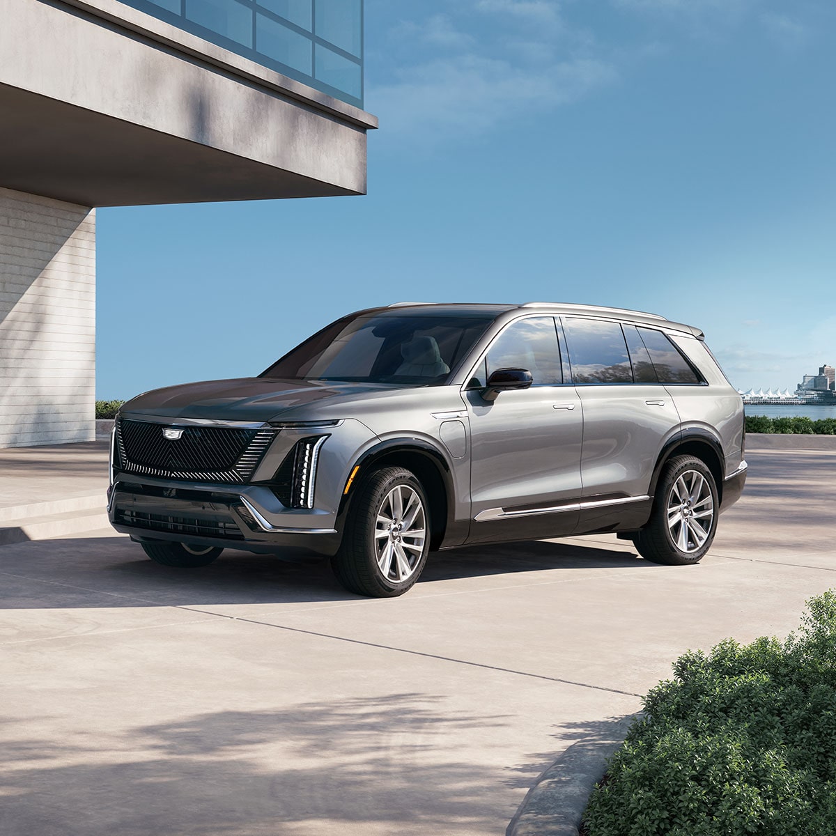 Three-quarters View of the 2027 Cadillac VISTIQ Parked Outside of a Concrete, Modern Building
