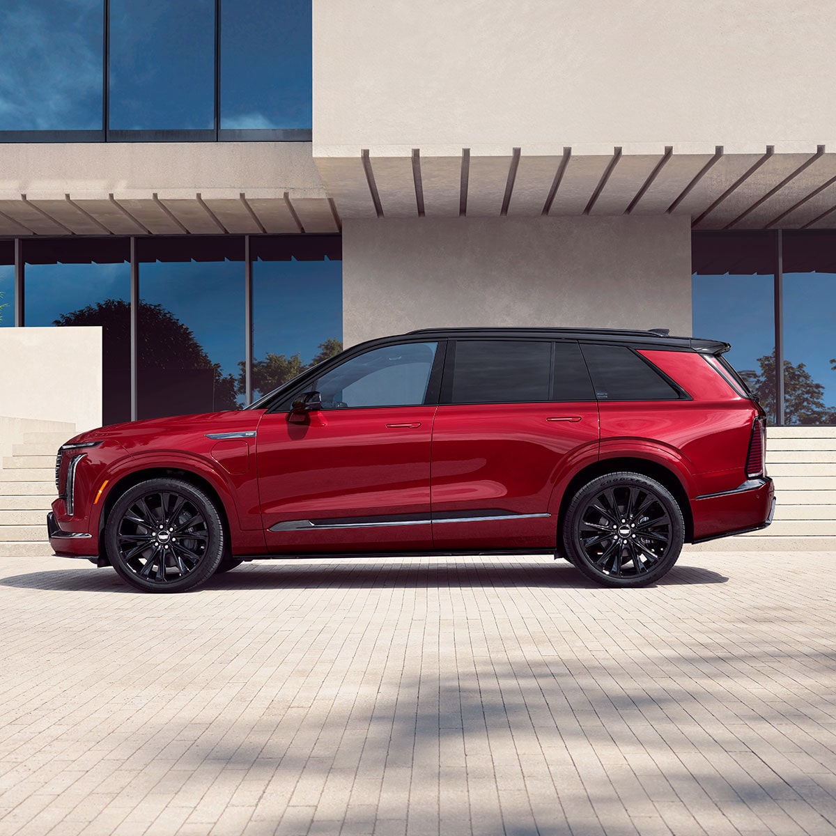 Profile View of the Red Cadillac VISTIQ Parked on a White Brick Driveway Outside a Modern Home