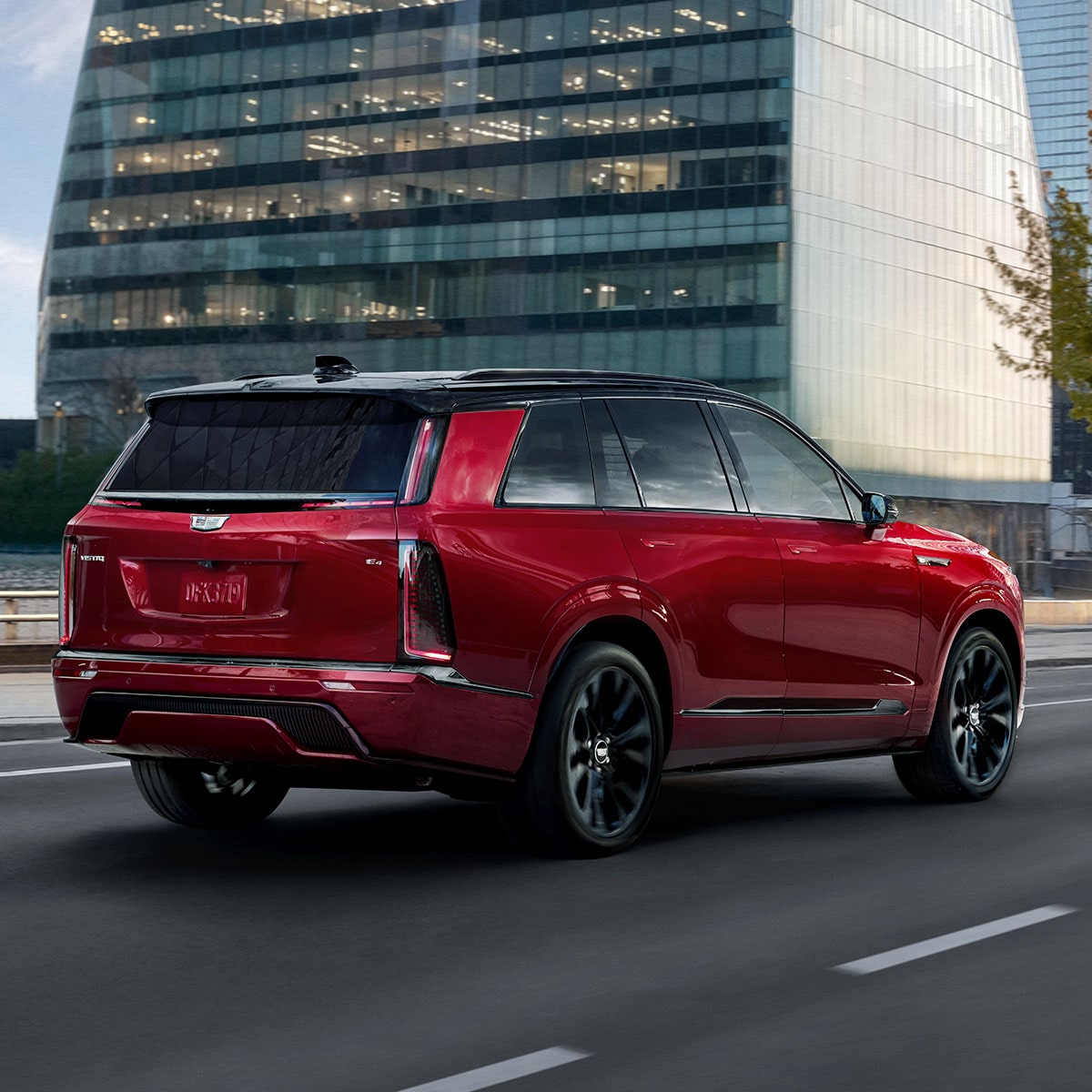 A Rear Three-Quarter View of a Red 2027 Cadillac VISTIQ Driving on a City Street