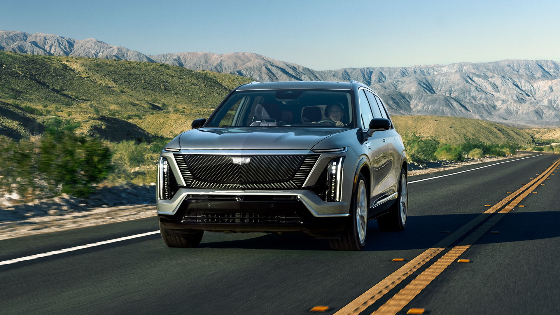 The Cadillac VISTIQ 3-row Electric SUV Driving Down a Road in the Mountains