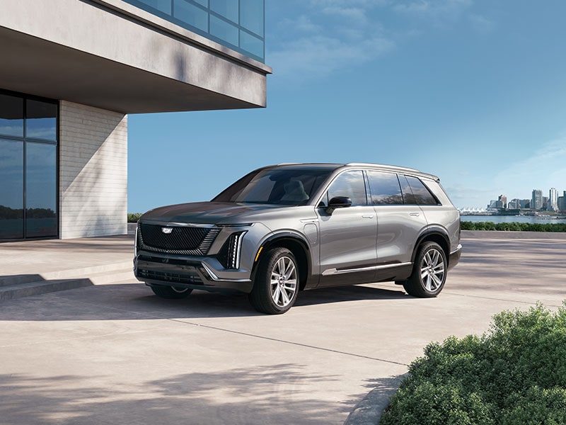 Three-quarters View of the 2027 Cadillac VISTIQ Parked Outside of a Concrete, Modern Building