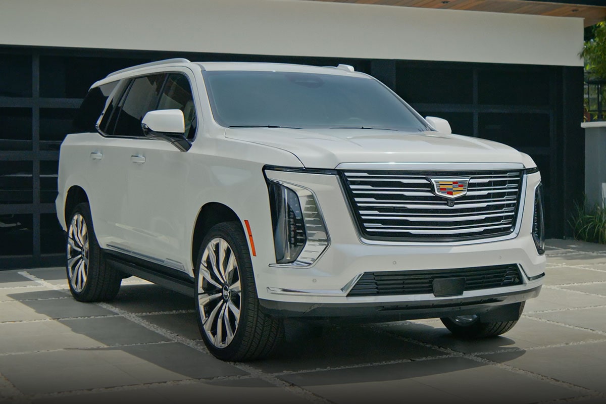 A 2027 White Cadillac Escalade Parked Outside a Modern Building Featuring a Chrome Grille and Vertical LED Lighting