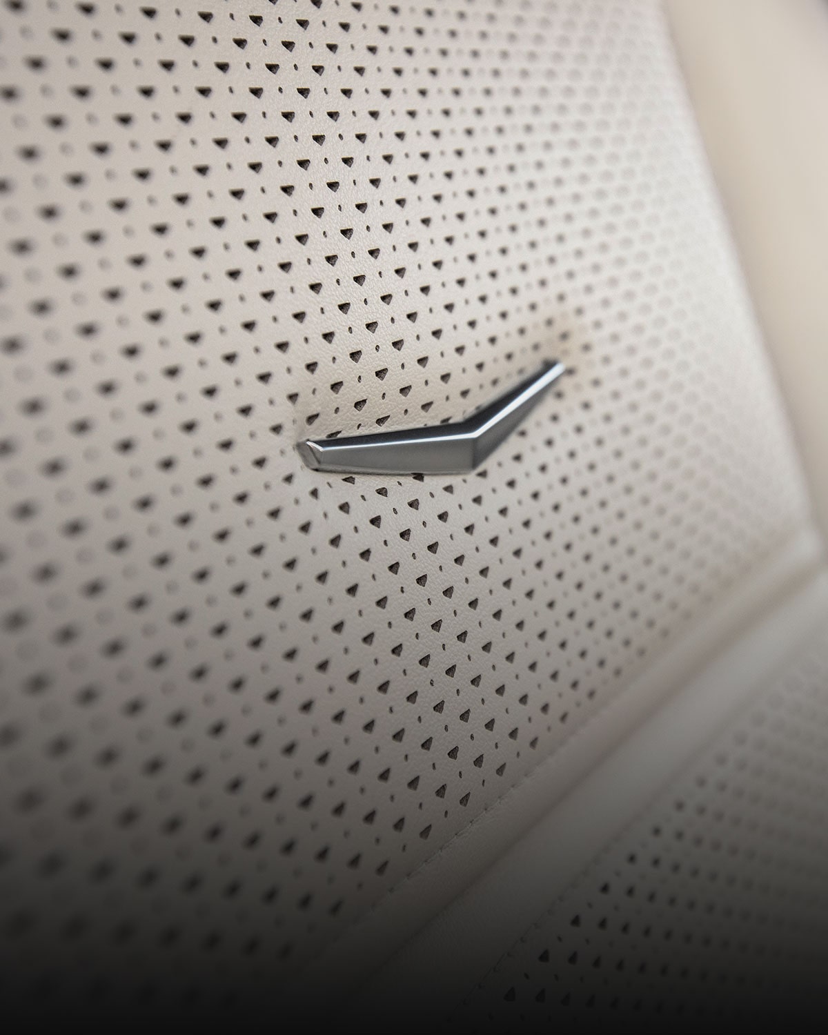 Close-Up View of a Cadillac Crest Emblem Embossed on the 2027 Escalade Perforated Light-Colored Leather Seat