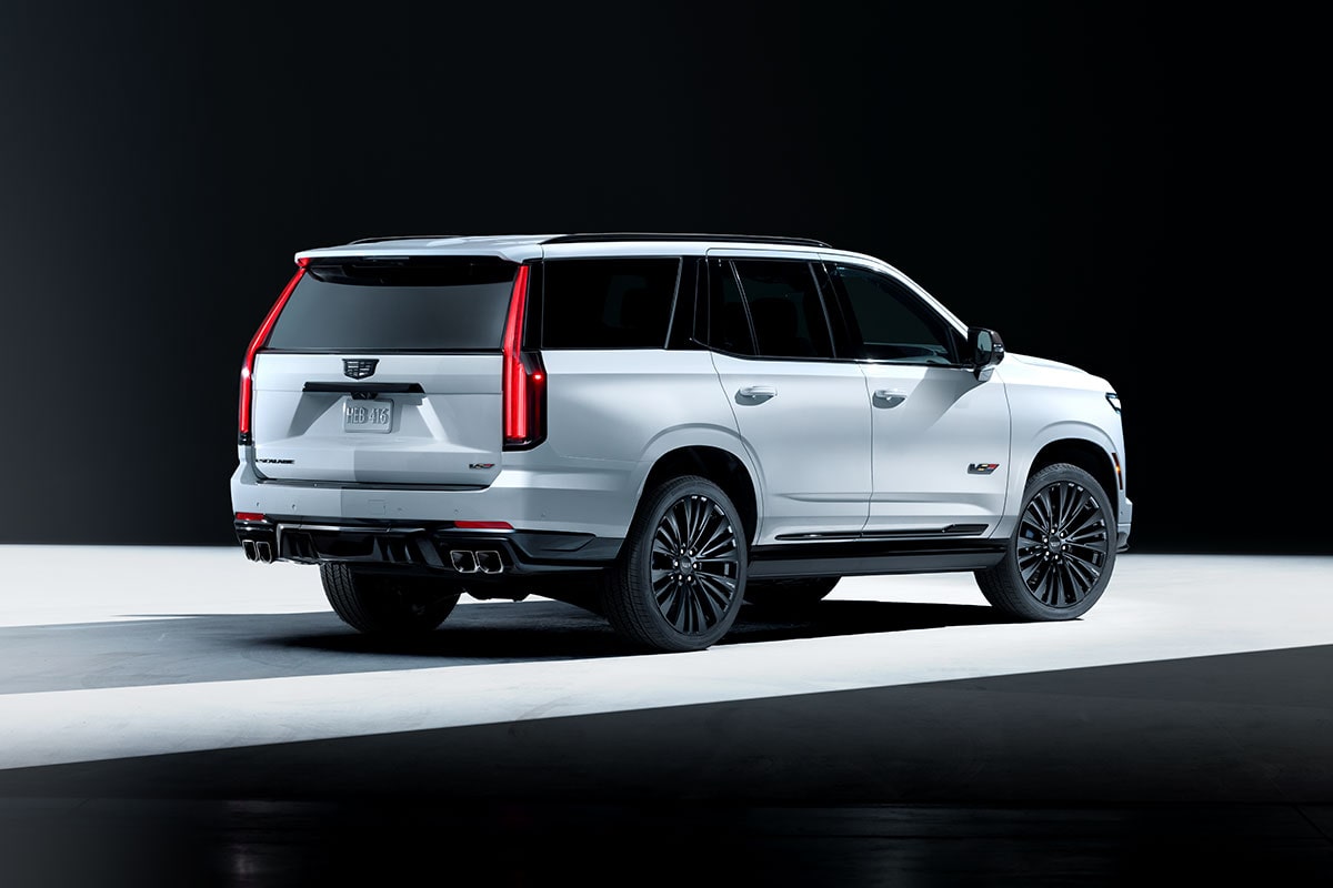 Three-quarter Rear View of a Light Shining on a White Cadillac Escalade-V Collector Series Parked in a Dark Showroom