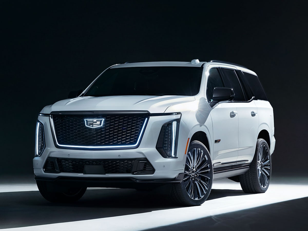 Three-quarter View of a Light Shining on a White Cadillac Escalade-V Parked in a Dark Showroom