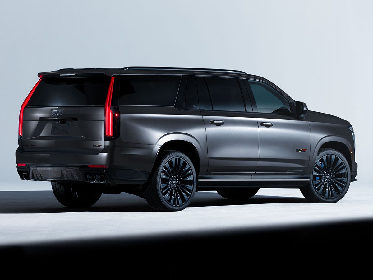 Three-quarter Rear View of a Light Shining on a Black Cadillac Escalade-V Collector Series Parked in a Dark Showroom