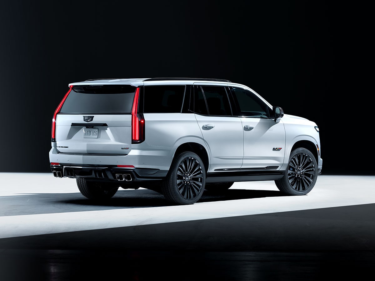 Three-quarter Rear View of a Light Shining on a White Cadillac Escalade-V Collector Series Parked in a Dark Showroom