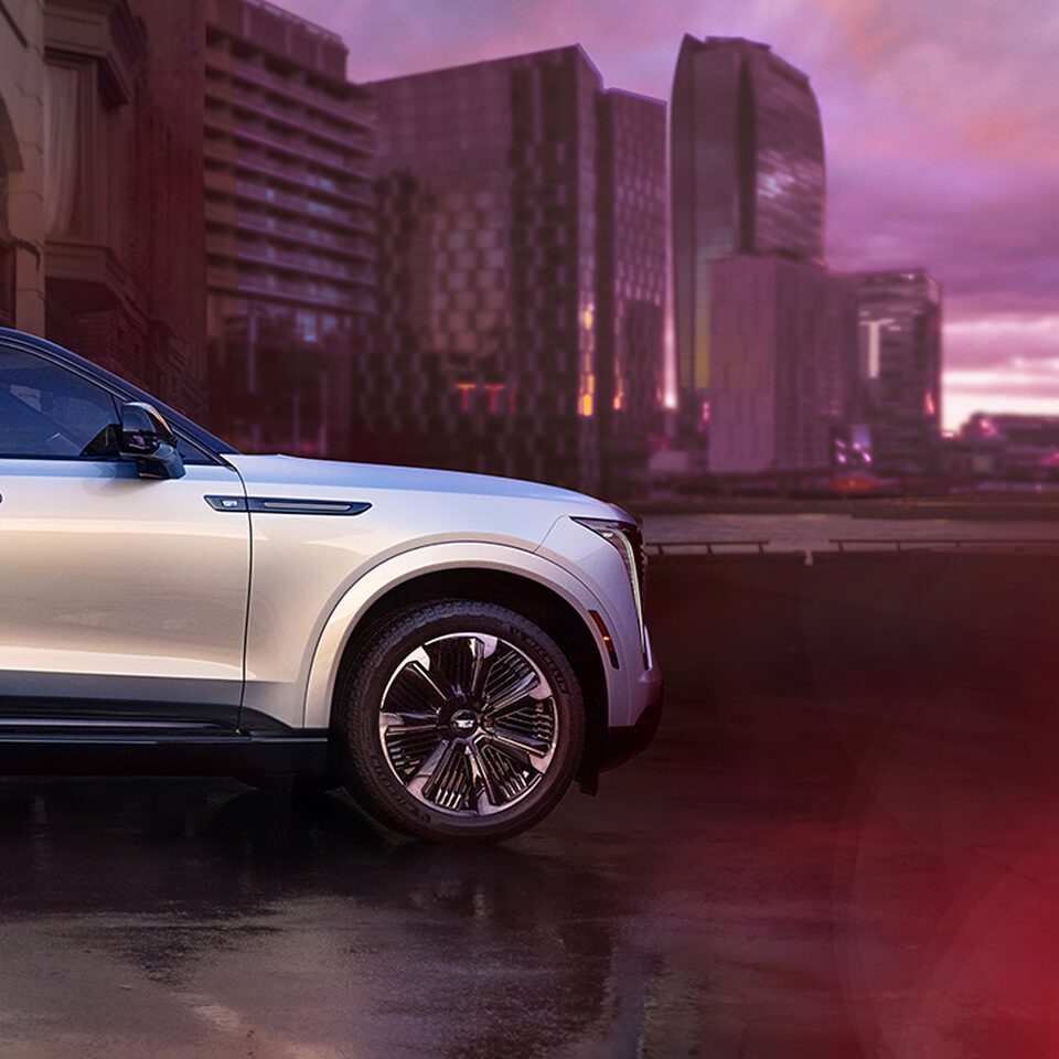 Side Profile of the 2025 Cadillac ESCALADE IQ Parked in Front of Buildings