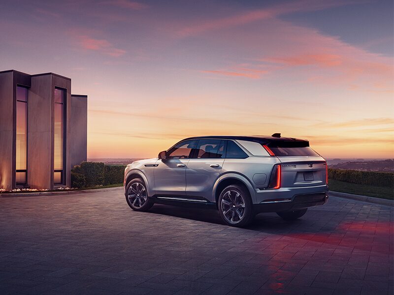 Exterior Driver Side View of the 2025 Cadillac ESCALADE IQ Parked in Front of a House at Sun Set