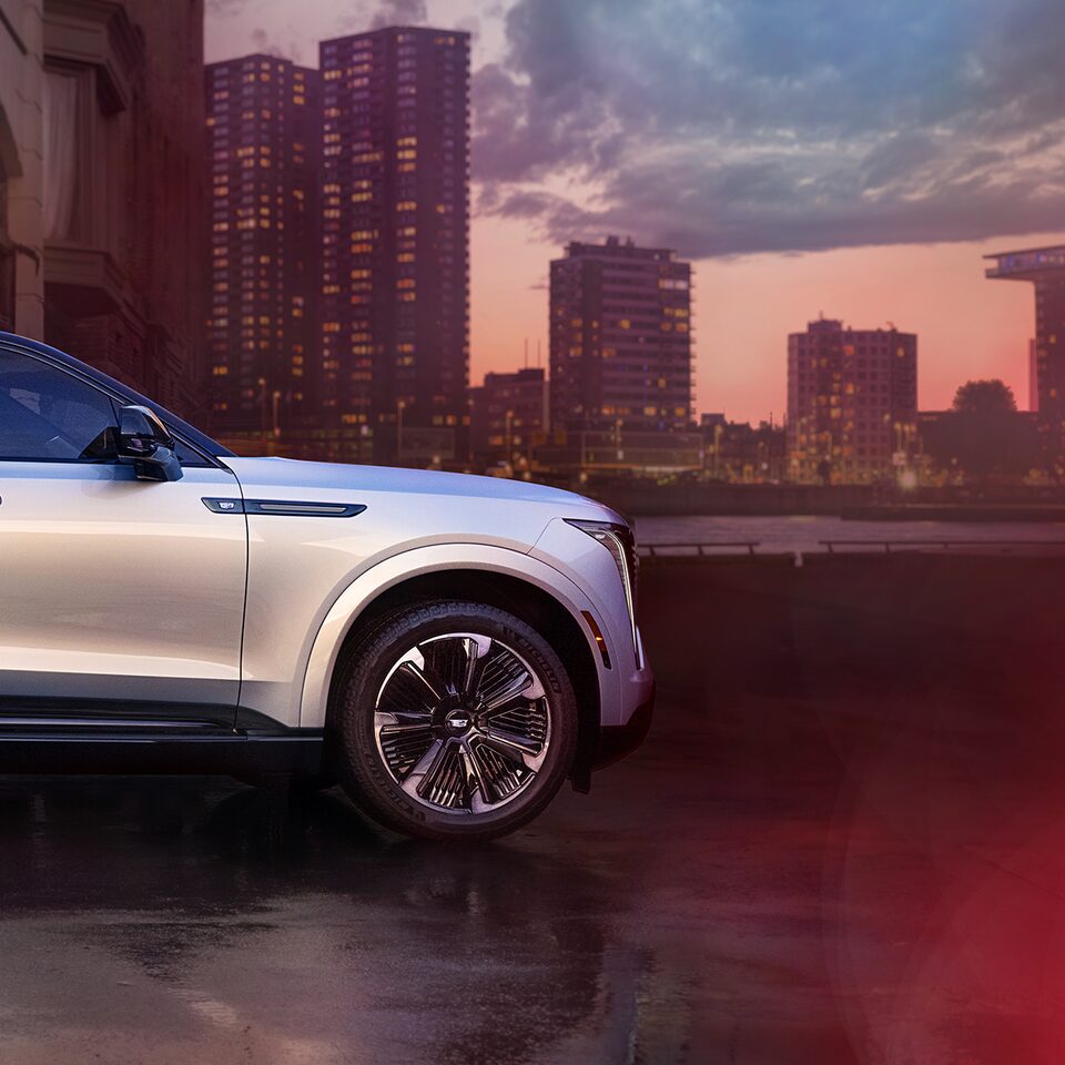 Side Profile of the 2025 Cadillac ESCALADE IQ Parked in Front of Buildings