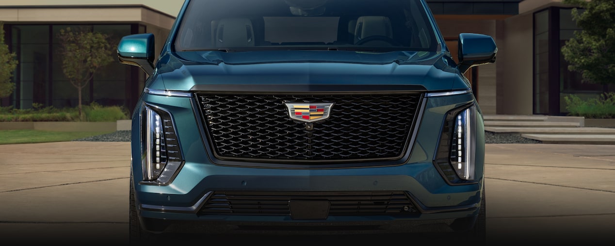 Vista delantera de la parrilla de Cadillac Escalade 2025 azul estacionada en una entrada de garaje