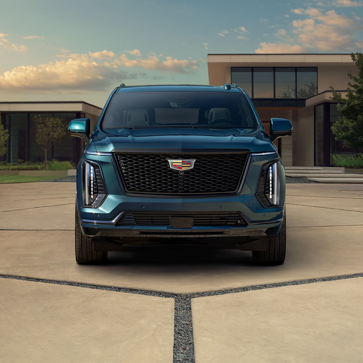 Vista delantera de la parrilla de Cadillac Escalade 2025 azul estacionada en una entrada de garaje