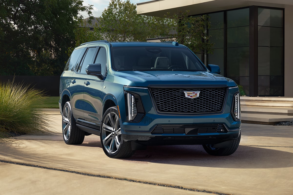 Three-Quarter View of a Blue 2025 Cadillac Escalade Parked in Front of a Modern Home