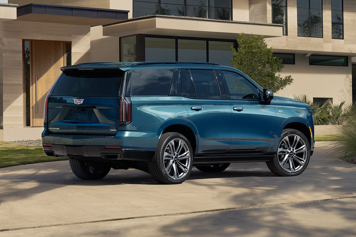 Three-Quarter Rear View of a Blue 2025 Cadillac Escalade Parked in Front of a Modern Home