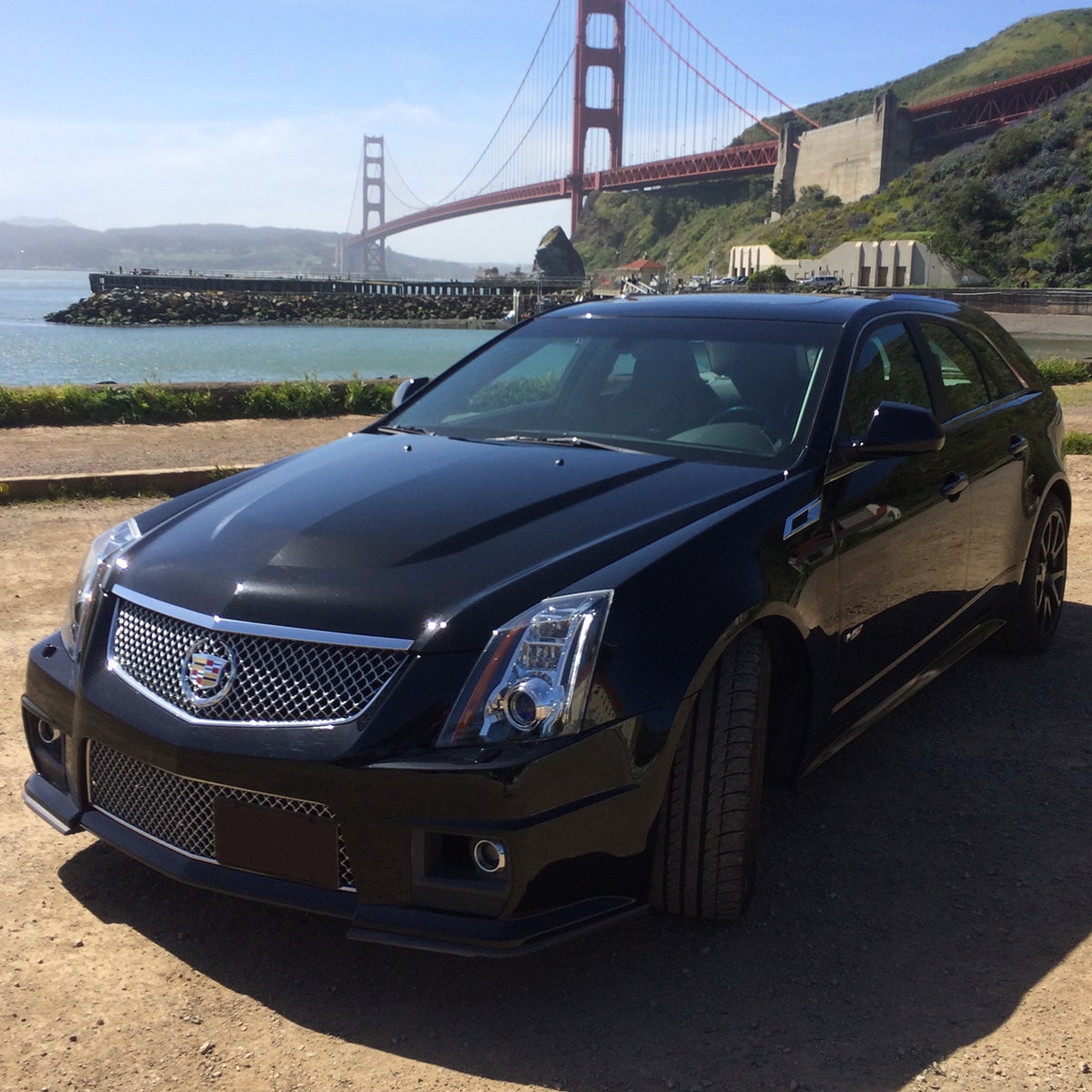 Cadillac V-Series Wagon en Negro estacionada en un camino de tierra debajo del puente Golden Gate de San Francisco