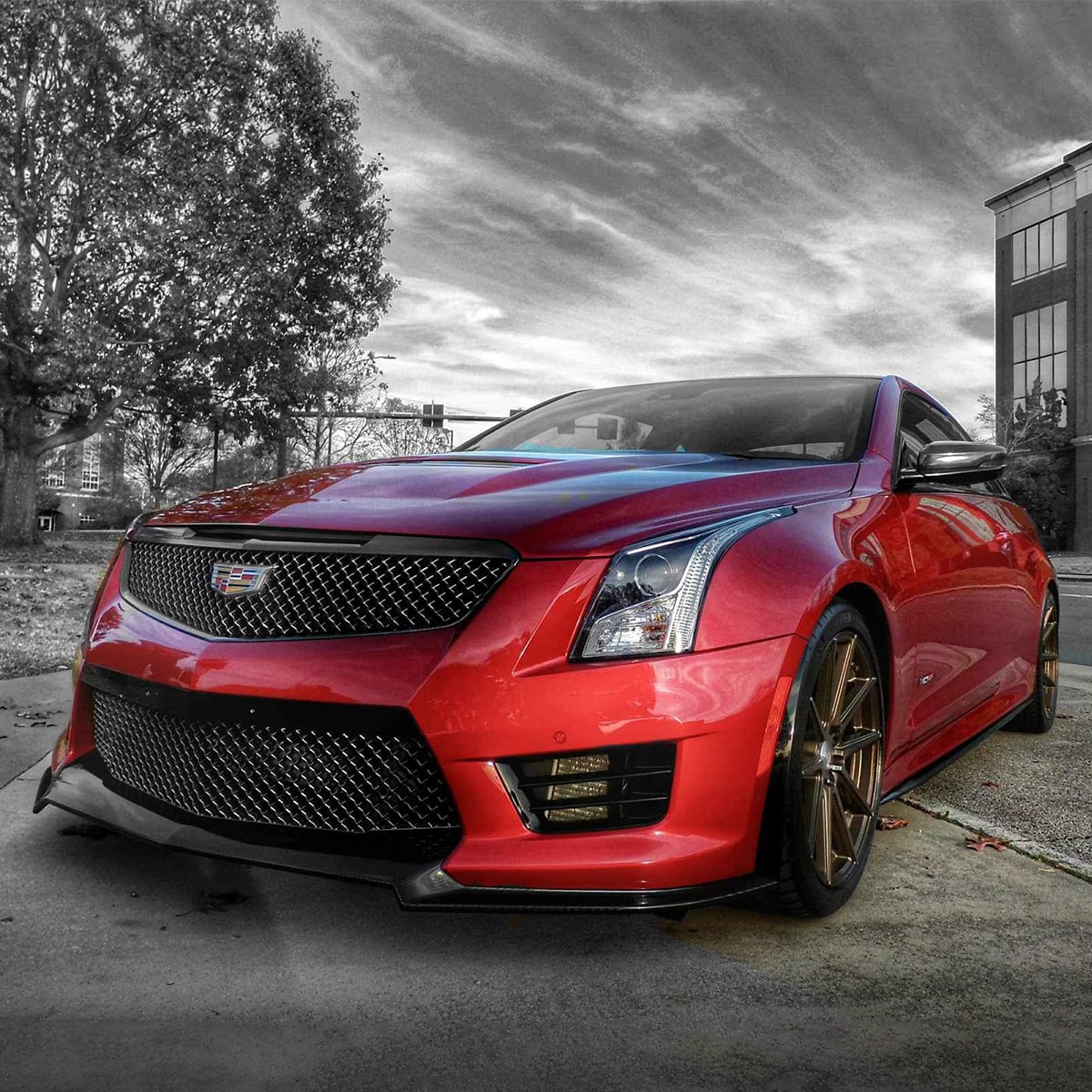 Vista frontal lateral de un sedán Cadillac V-Series en Rojo estacionado sobre cemento