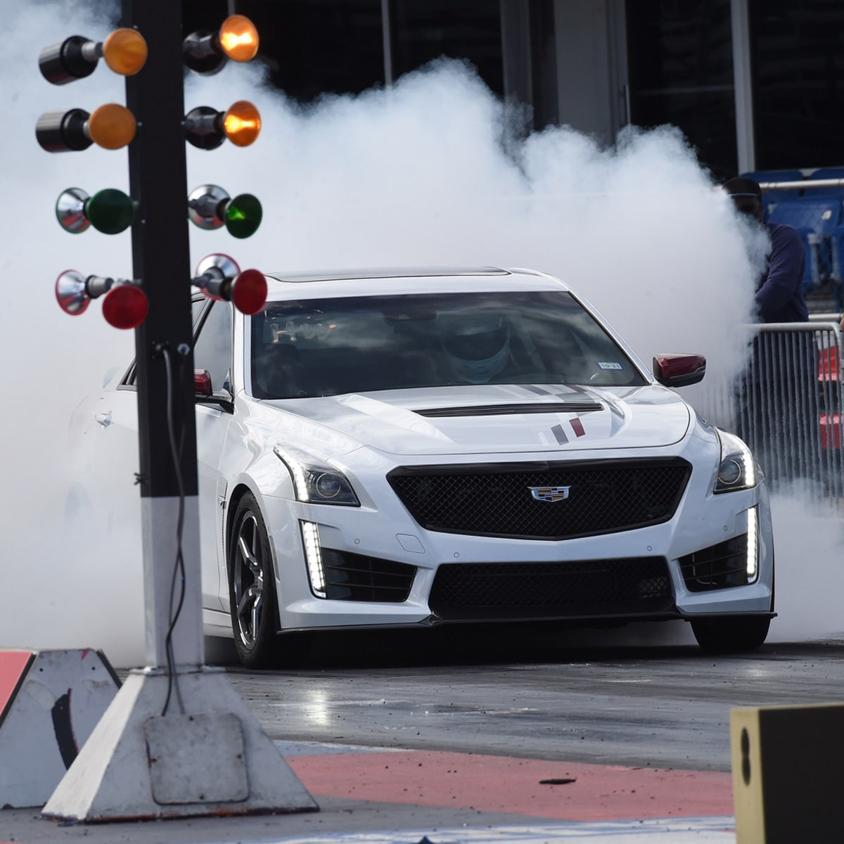 Cadillac V-Series en Blanco quemando neumáticos al lado del semáforo de una pista de carreras