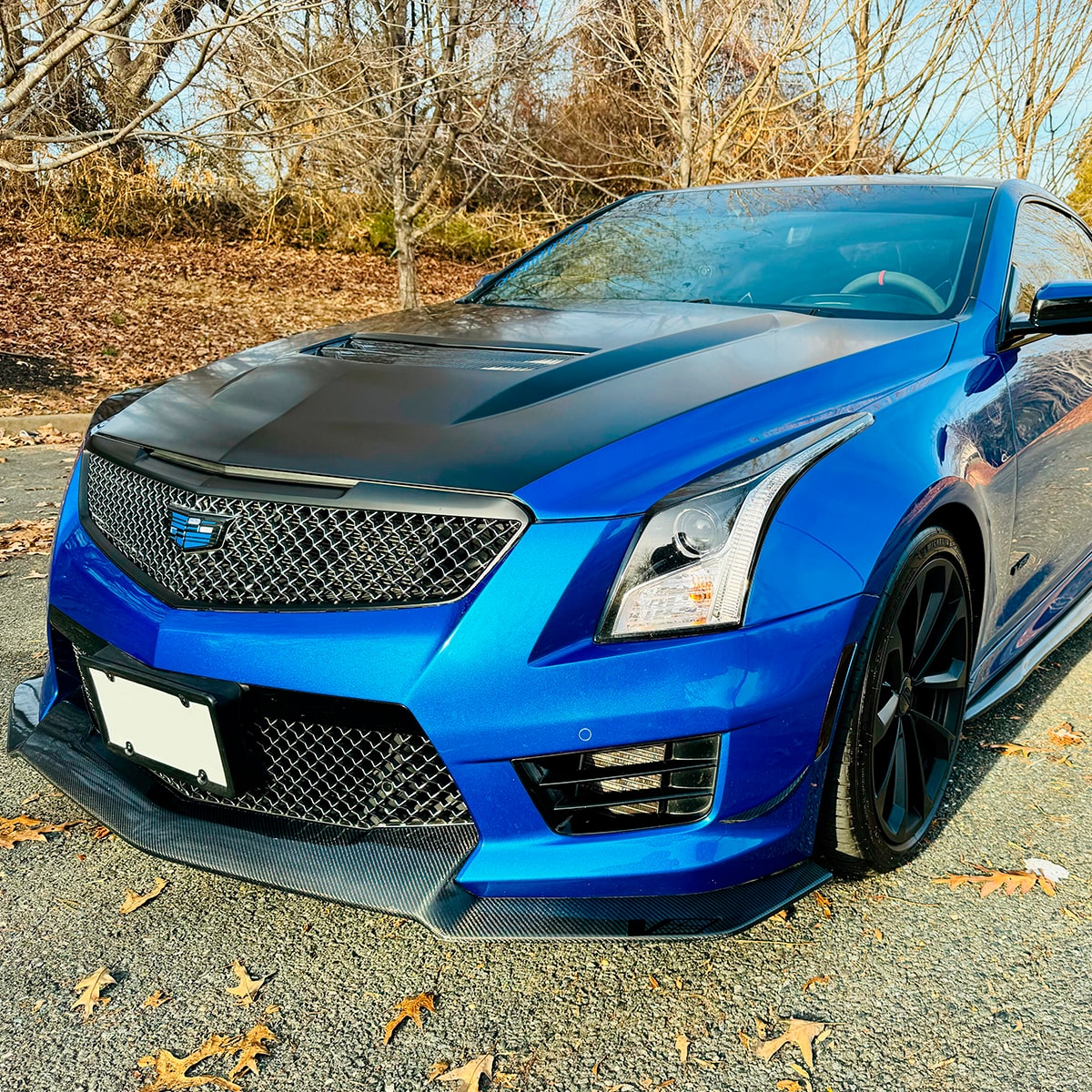 Vista delantera de Cadillac ATS-V azul estacionado en un camino cerca del bosque