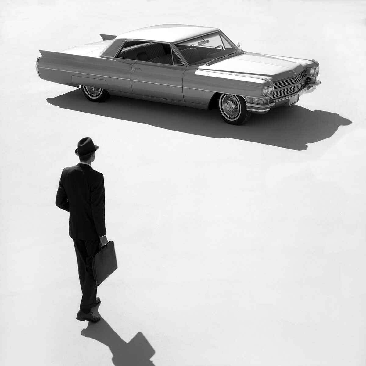 Black & White Overview of a Business Man Walking Towards a 1964 Cadillac Series 62 Coupe