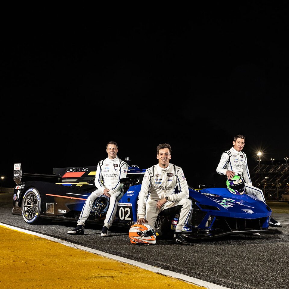 Three Cadillac Drivers Stand Besides the V-Series.R Electrified Race Car