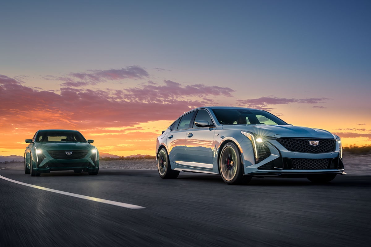 A CT4-V Blackwing and a CT5-V Blackwing Driving Down a Road with a Sunset in the Rear View