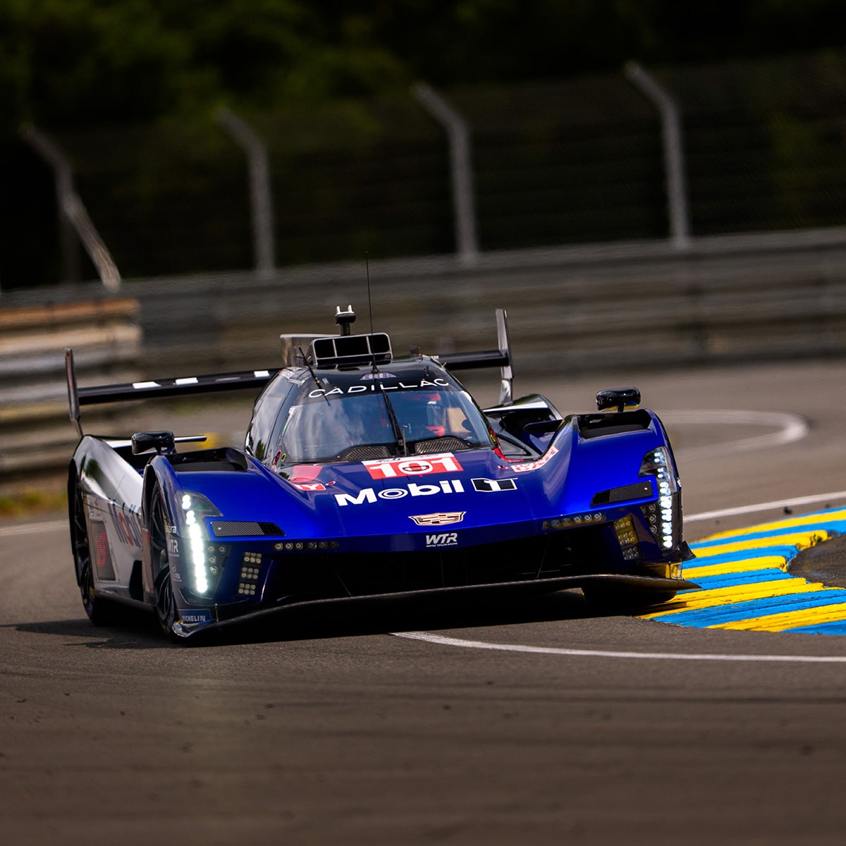 Front View of the Blue Cadillac V-Series.R Race Car Driving Around the Curve of a Track