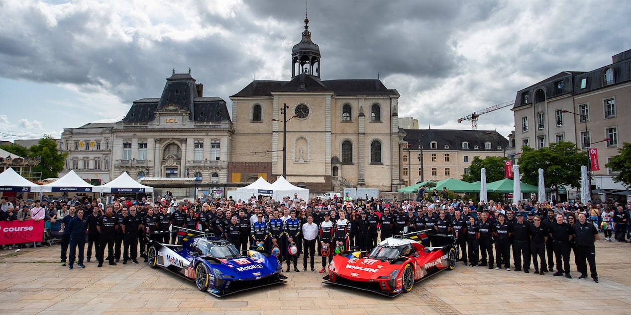 Bird's Eye View of the Entire Cadillac Race Team Posing for a Picture Behind Two Parked V-Series.R Race Cars