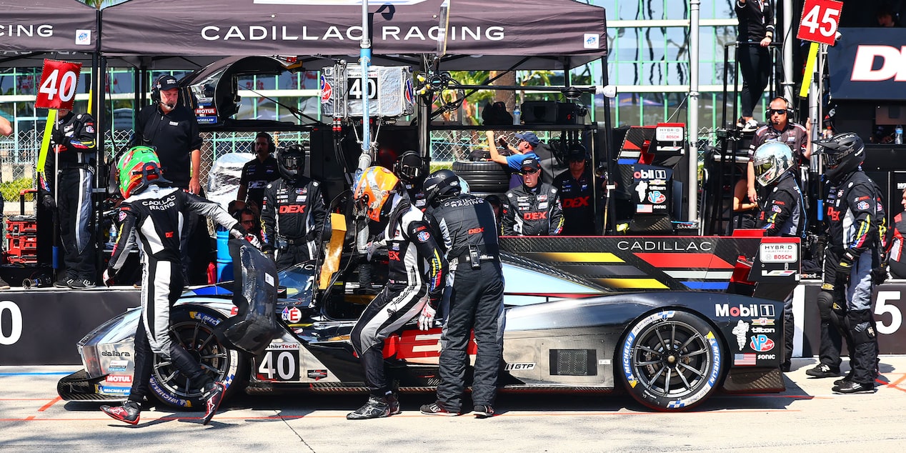 A Driver Getting into the Parked Silver Cadillac V-Series.R Race Car