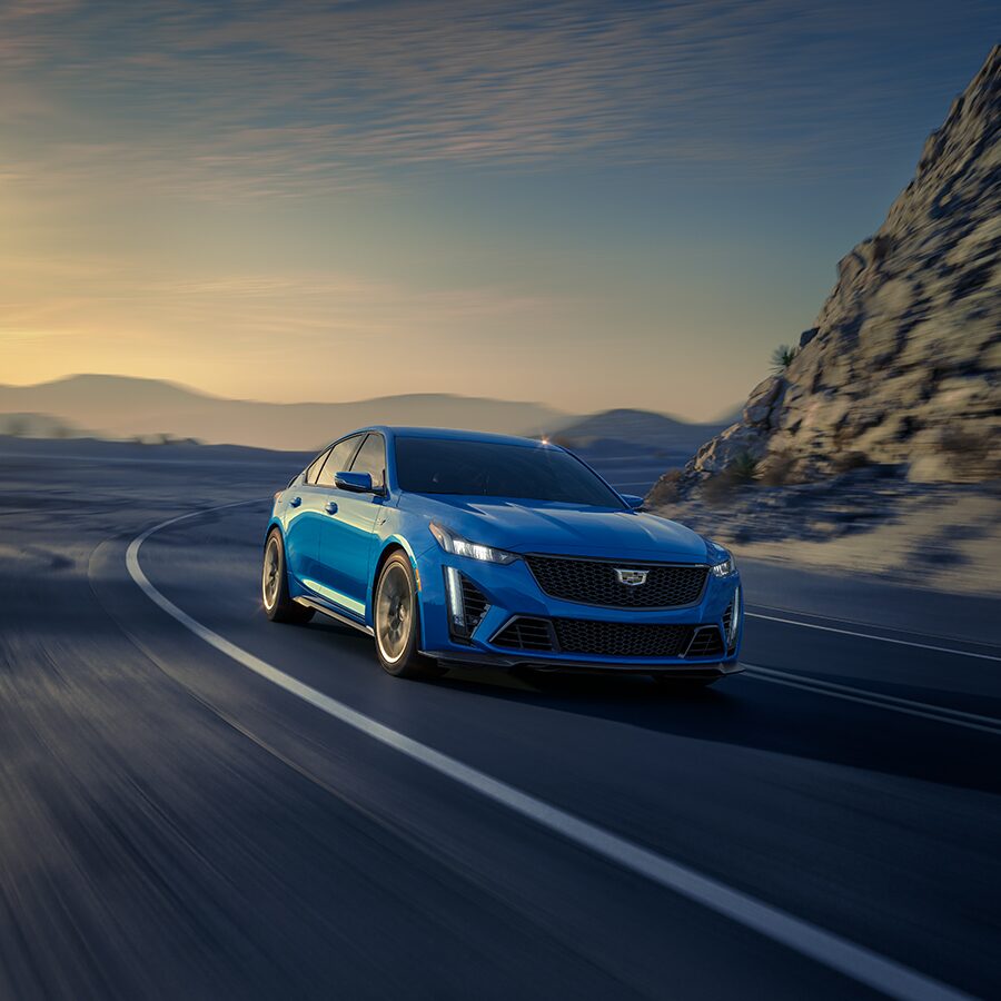 2024 Cadillac CT5-V Blackwing Speeding Around a Bend in The Road With Mountains in The Background