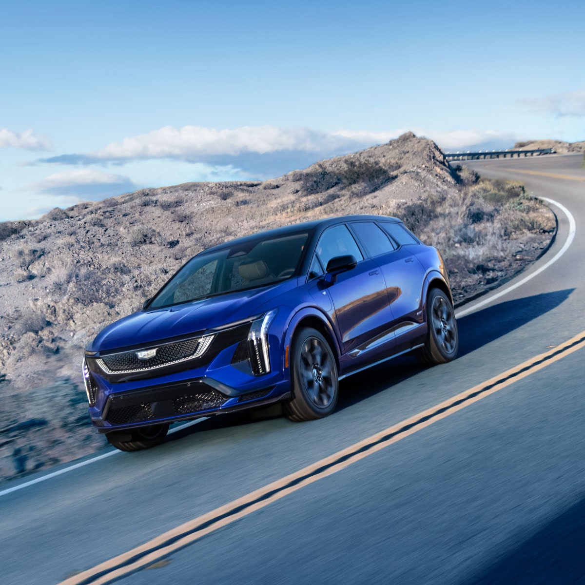 A Blue CT5-V Performance Sedan Racing Around the Curve of a Mountain