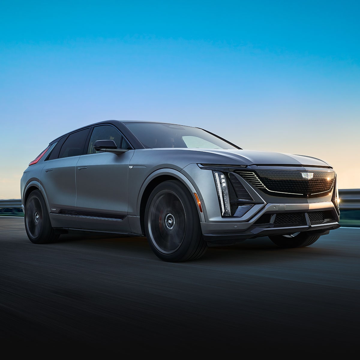 A Silver 2026 LYRIQ-V Driving Down a Highway with a Clear Blue Sky in the Background