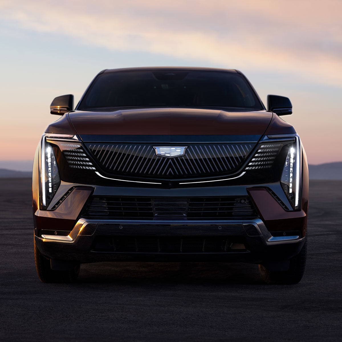 Front View of the 2026 ESCALADE IQ Parked in the Desert at Dusk with the Slimline LED Lights On