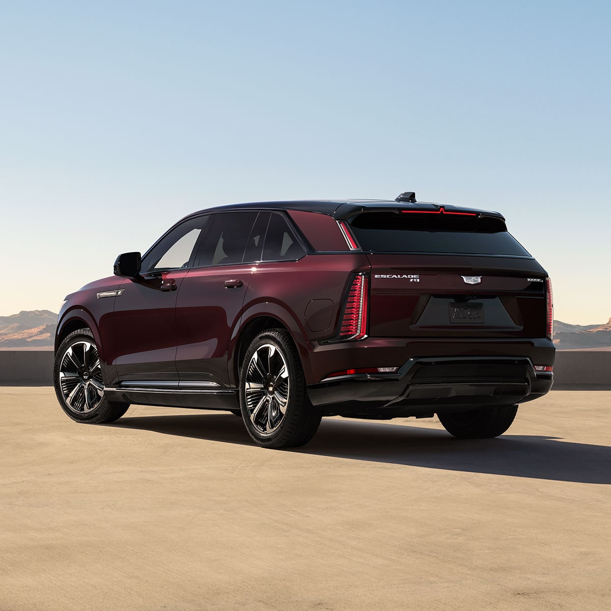 Three-quarters Rear End View of a Maroon 2026 ESCALADE IQ Parked in the Desert