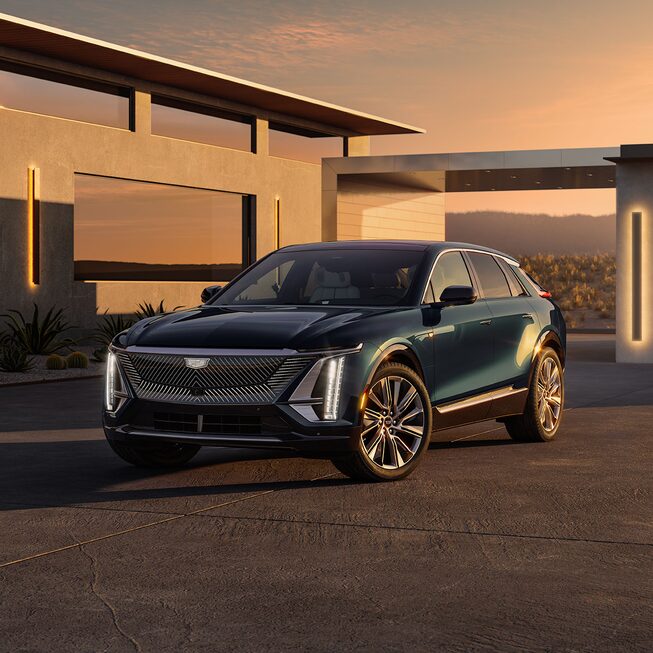 2024 Cadillac LYRIQ Luxury in Emerald Green Metallic parked in front of modern concrete home.