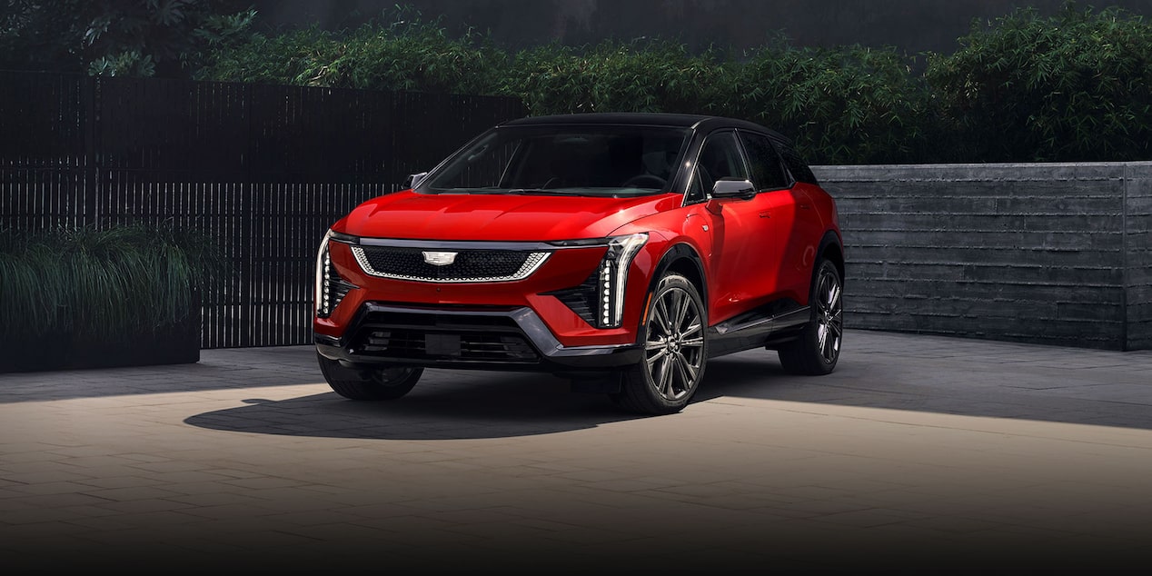 Three-quarter View of a Red 2025 Cadillac OPTIQ Parked Outside of a Business Building