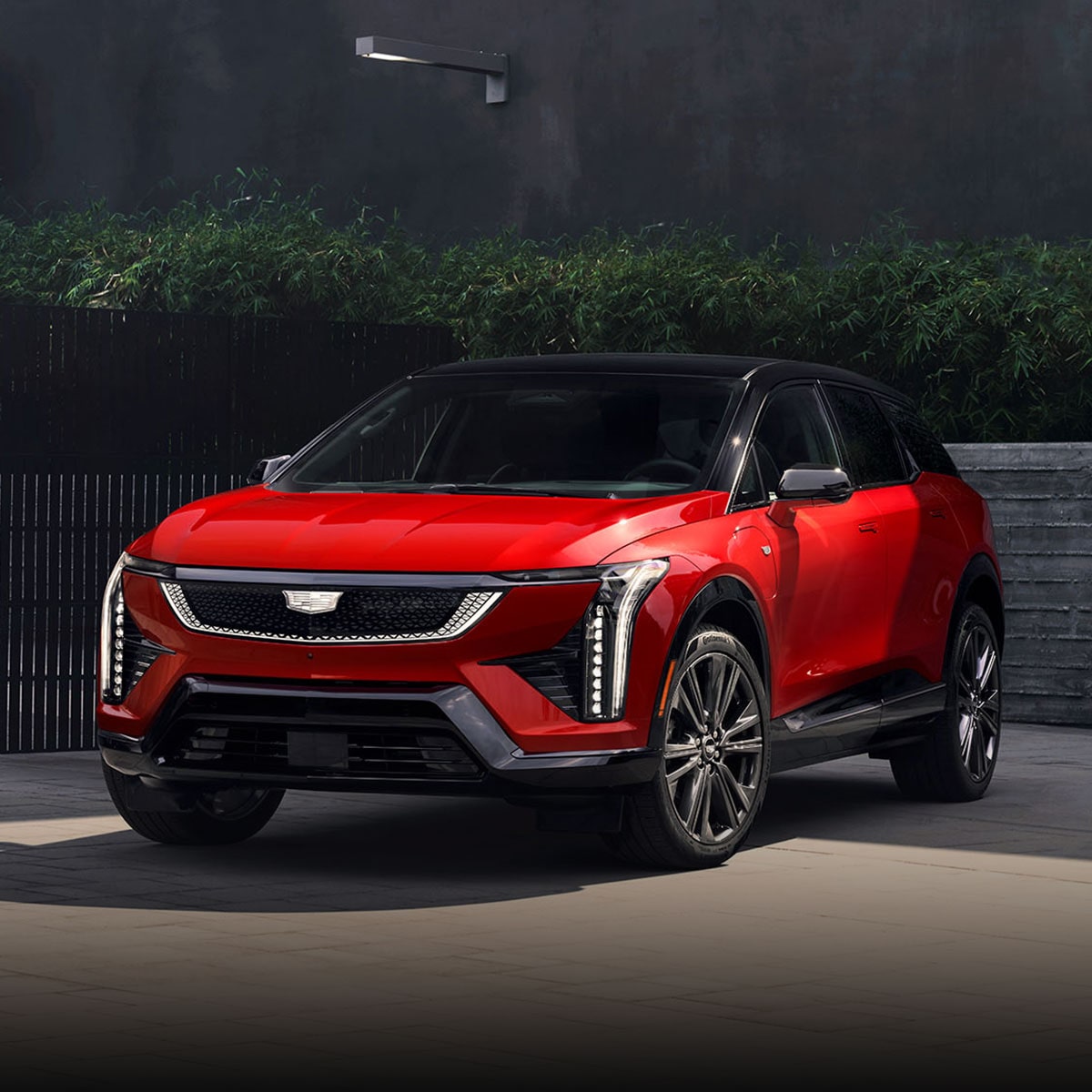 Three-quarter View of a Red 2025 Cadillac OPTIQ Parked Outside of a Business Building