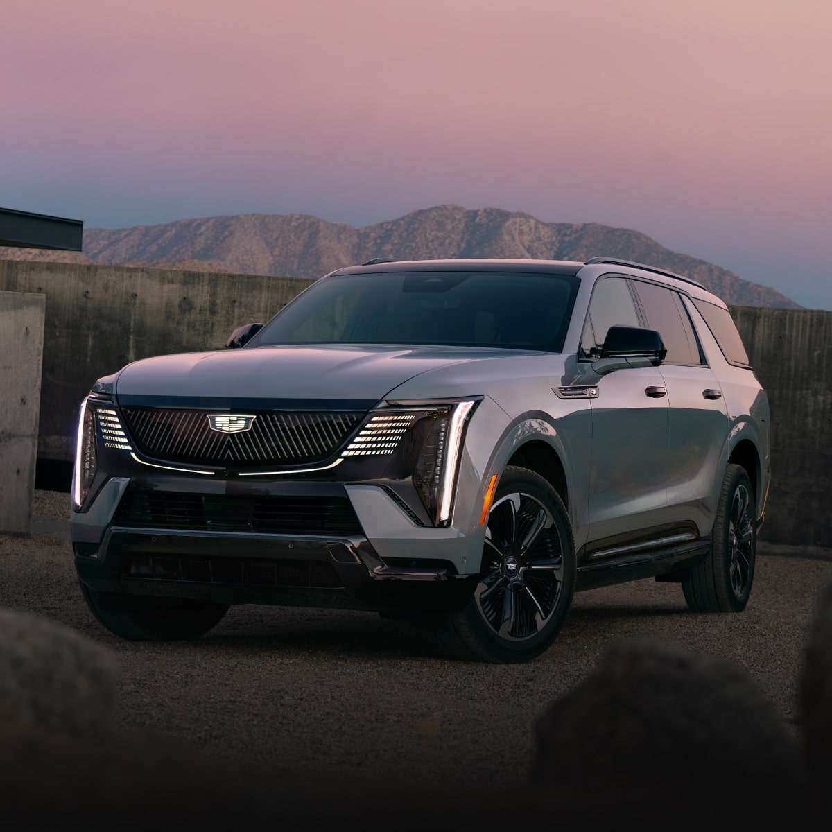Front Three-Quarter View of the 2026 ESCALADE IQL Parked near a Concrete Wall During Dusk